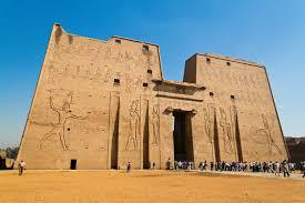 A large stone building with carvings on the side with Temple of Edfu in the background

AI-generated content may be incorrect.