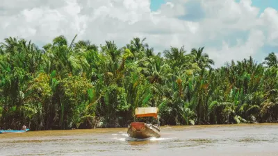 Ben Tre Tour | The Secret of The Coconuts “Capital” - A traditional Mekong Smile tour boat navigating through dense coconut palm trees in a Ben Tre canal. - 18713
