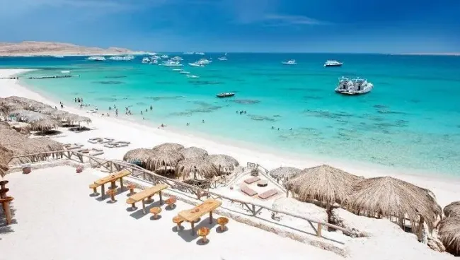 A beach with umbrellas and chairs and boats in the water

AI-generated content may be incorrect.